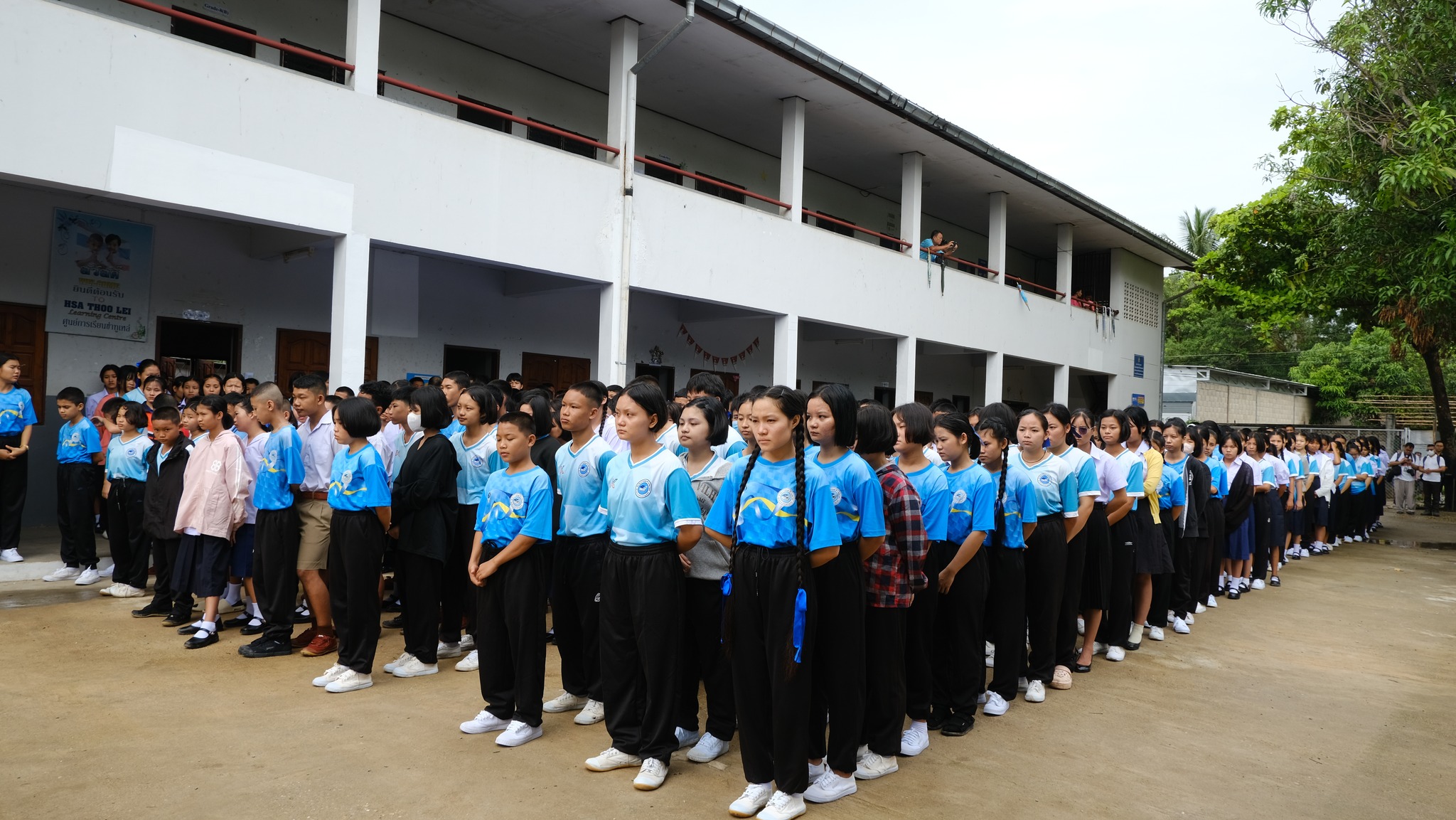 Students gathered in front of the school building Photo 1